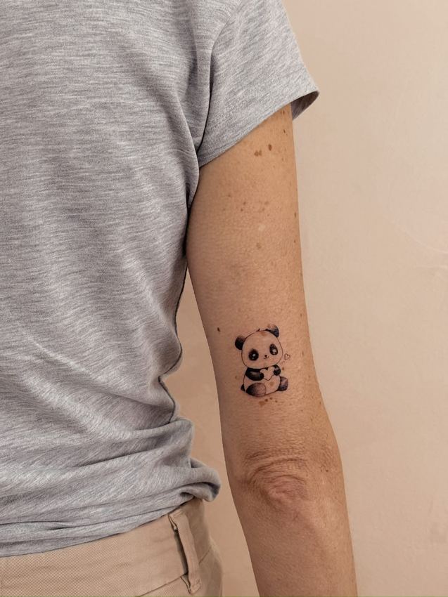 Tatuaje pequeño a color de un panda sentado, en el brazo