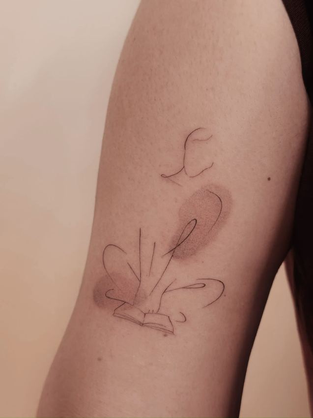 Tatuaje fine line abstracto con trazos sueltos y manchas de acuarela gris, en el brazo