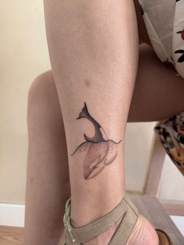 Tatuaje fine line de una ballena con sombreado suave, en la pierna