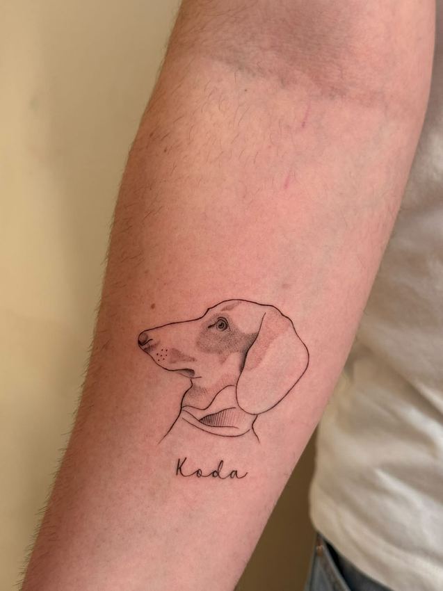 Tatuaje fine line del retrato de un perro salchicha con su nombre, en el antebrazo