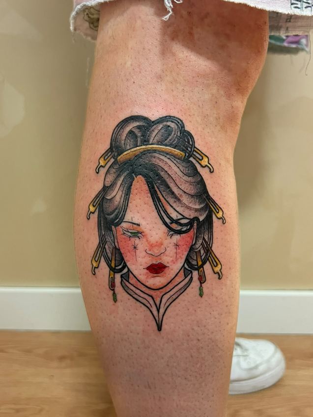 Tatuaje neotradicional a color con el retrato de una geisha, en el gemelo