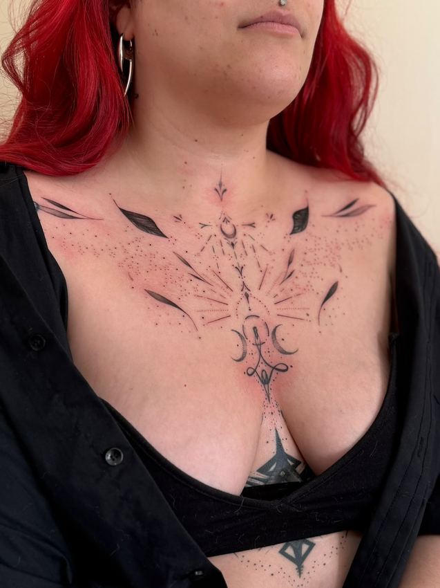 Tatuaje ornamental fine line simétrico con luna y puntillismo, en el pecho y las clavículas